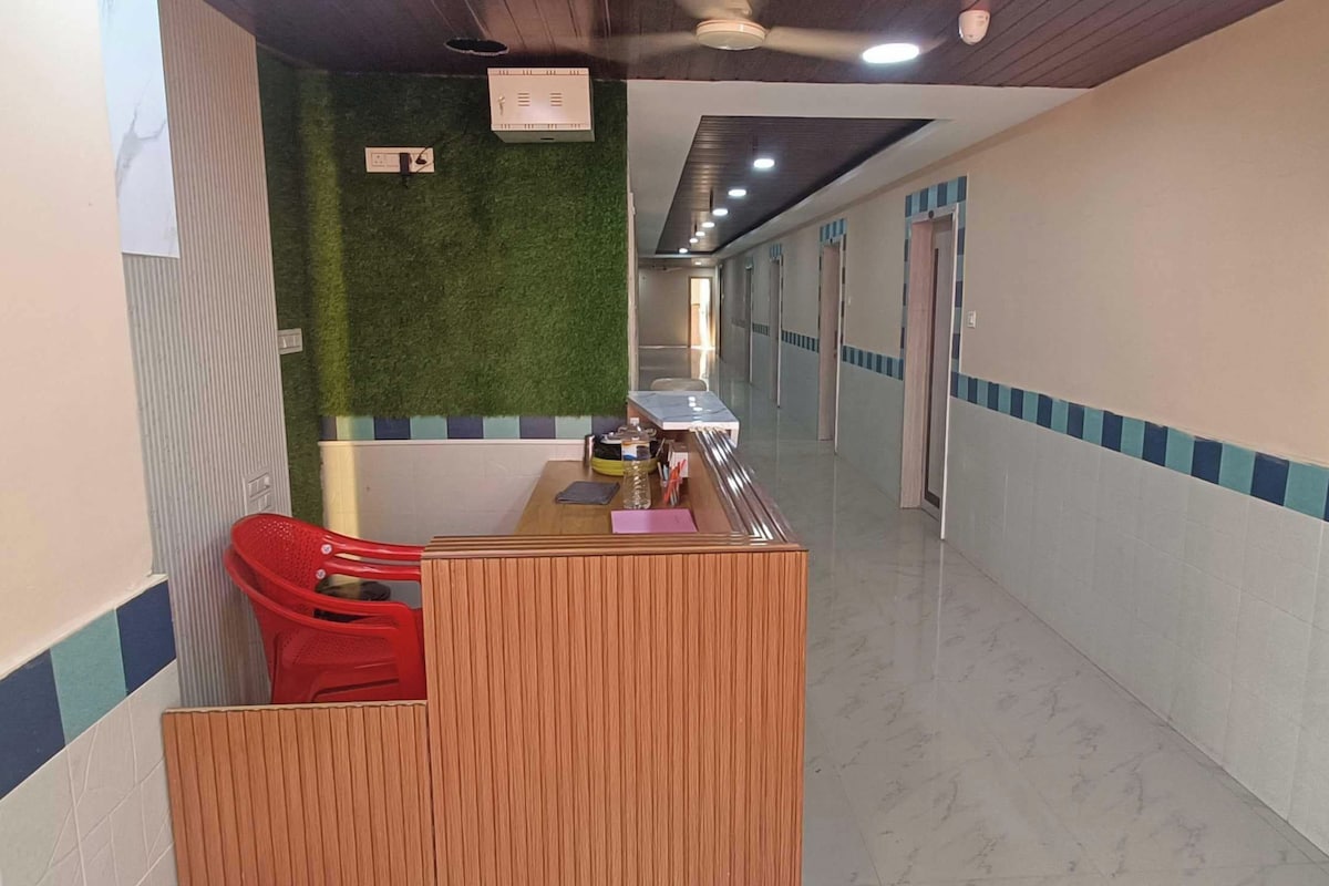 A reception area with a wooden desk, a red chair, and a green wall.
