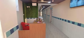 A reception area with a wooden desk, a red chair, and a green wall. - Hotel O Holiday Inn (Hyderabad)