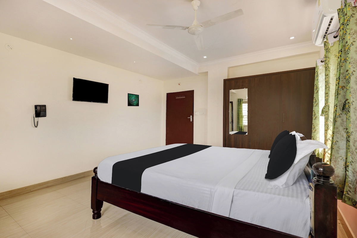 Una habitación de hotel con una cama, un televisor de pantalla plana, un teléfono y una puerta.
