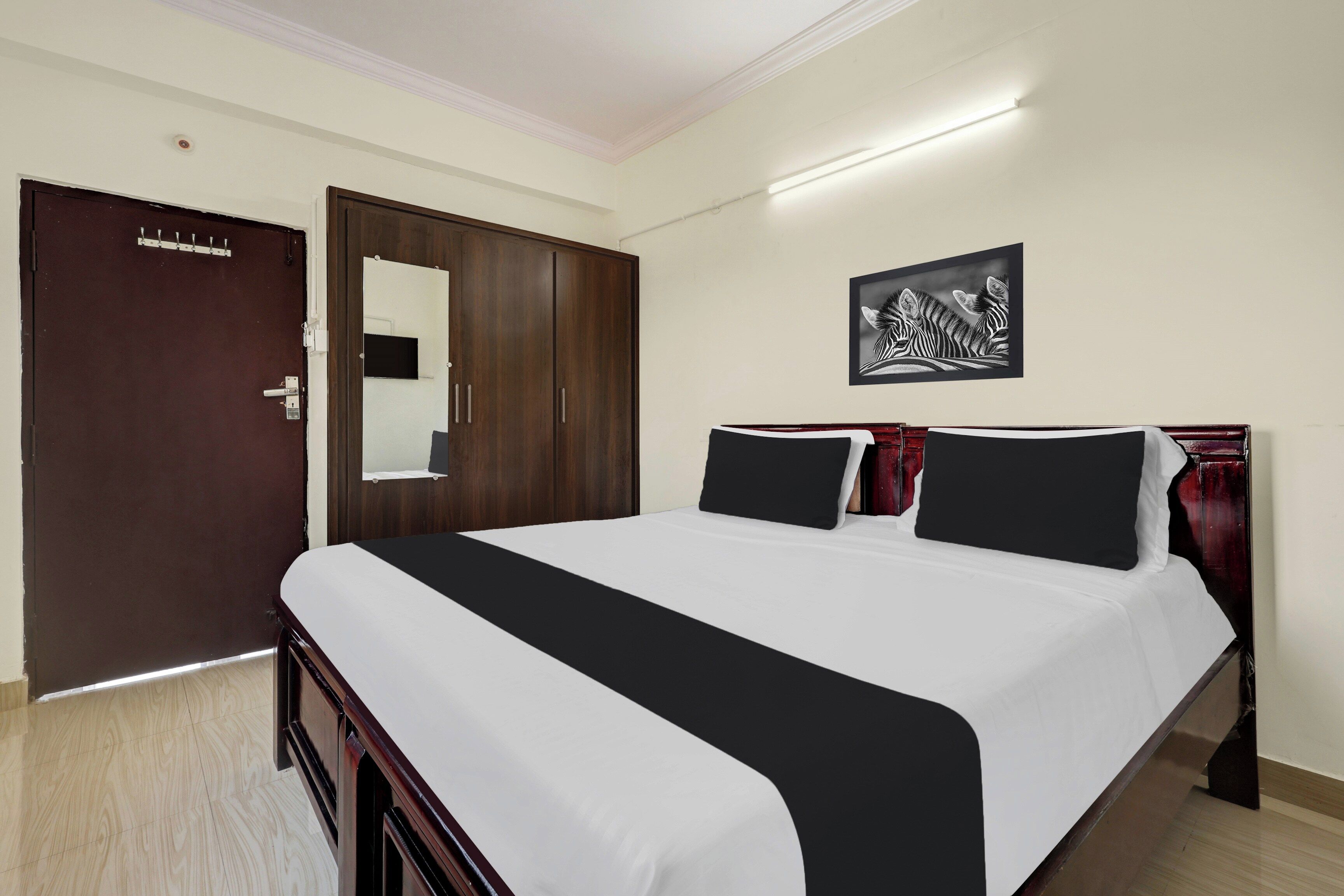 Habitación de hotel con una cama grande, un armario, un espejo y una obra de arte con temática de cebra en la pared.