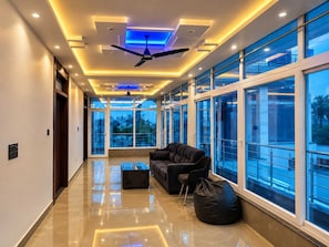 Un interior moderno con ventilador de techo, ventanas amplias y una zona de estar con sofá y sillón de felpa.