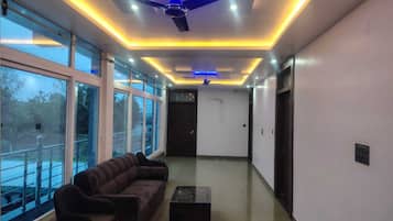 A modern lobby with a ceiling fan, seating area, and large windows.