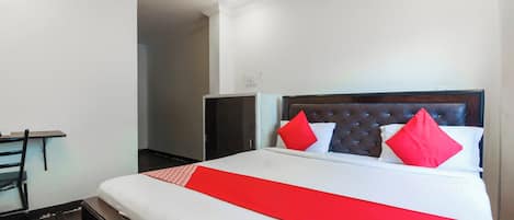 Quarto de hotel com cama, escrivaninha e guarda-roupa.