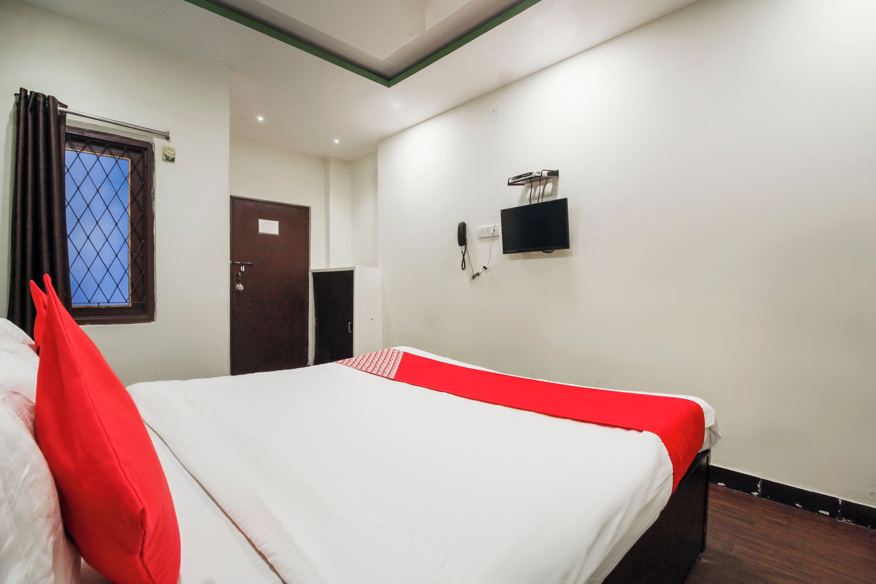 A hotel room with a bed, a television, and a door.
