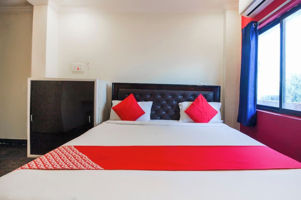 A hotel room with a bed, a wardrobe, and a window with curtains.