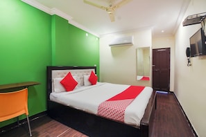 A hotel room with a bed, a desk, a chair, a television, and an air conditioning unit. - Hotel O Happy Guest House near LV Prasad (Hyderabad)