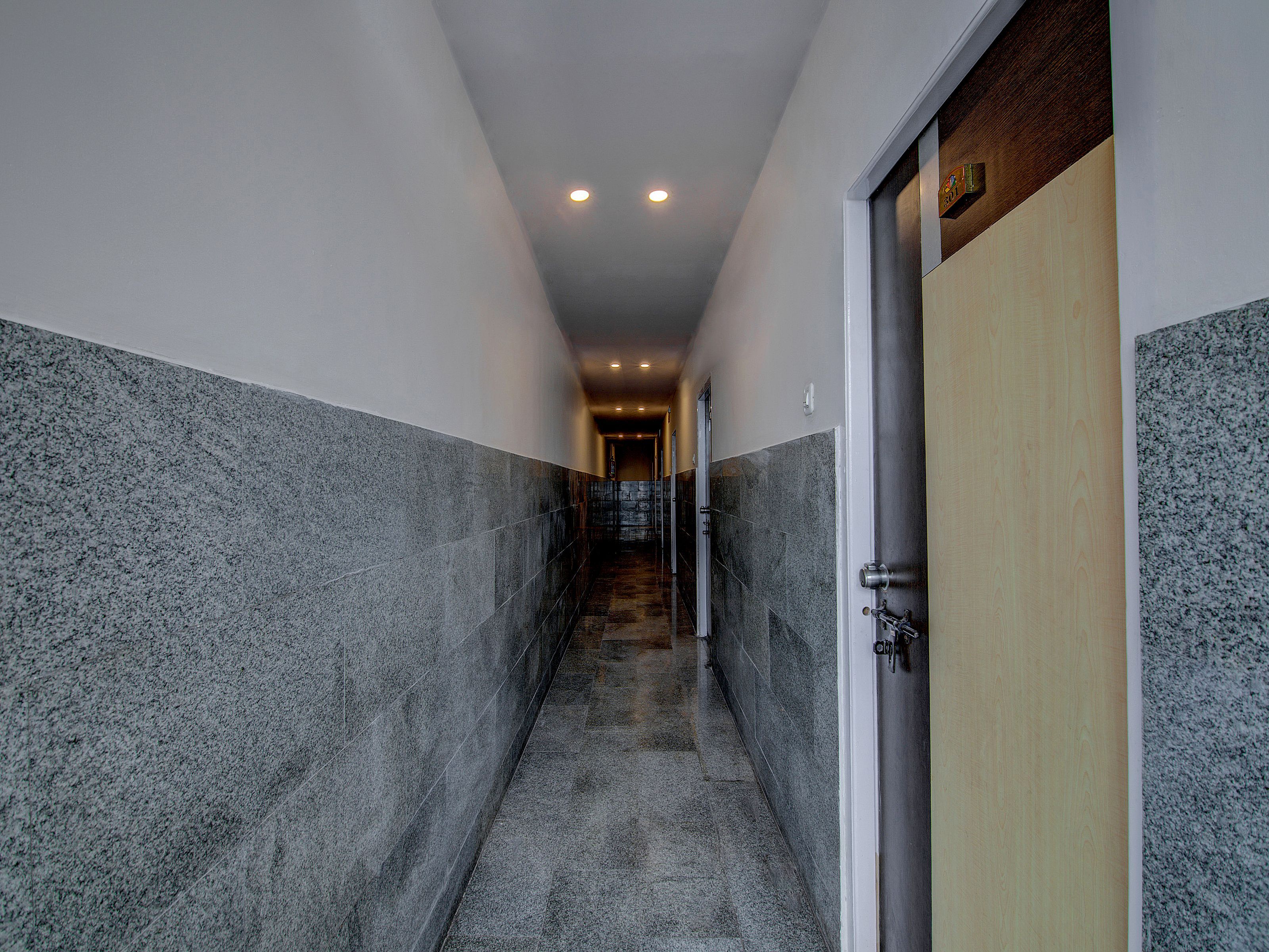 A hallway with a marble wall, a wooden door, and a ceiling light.
