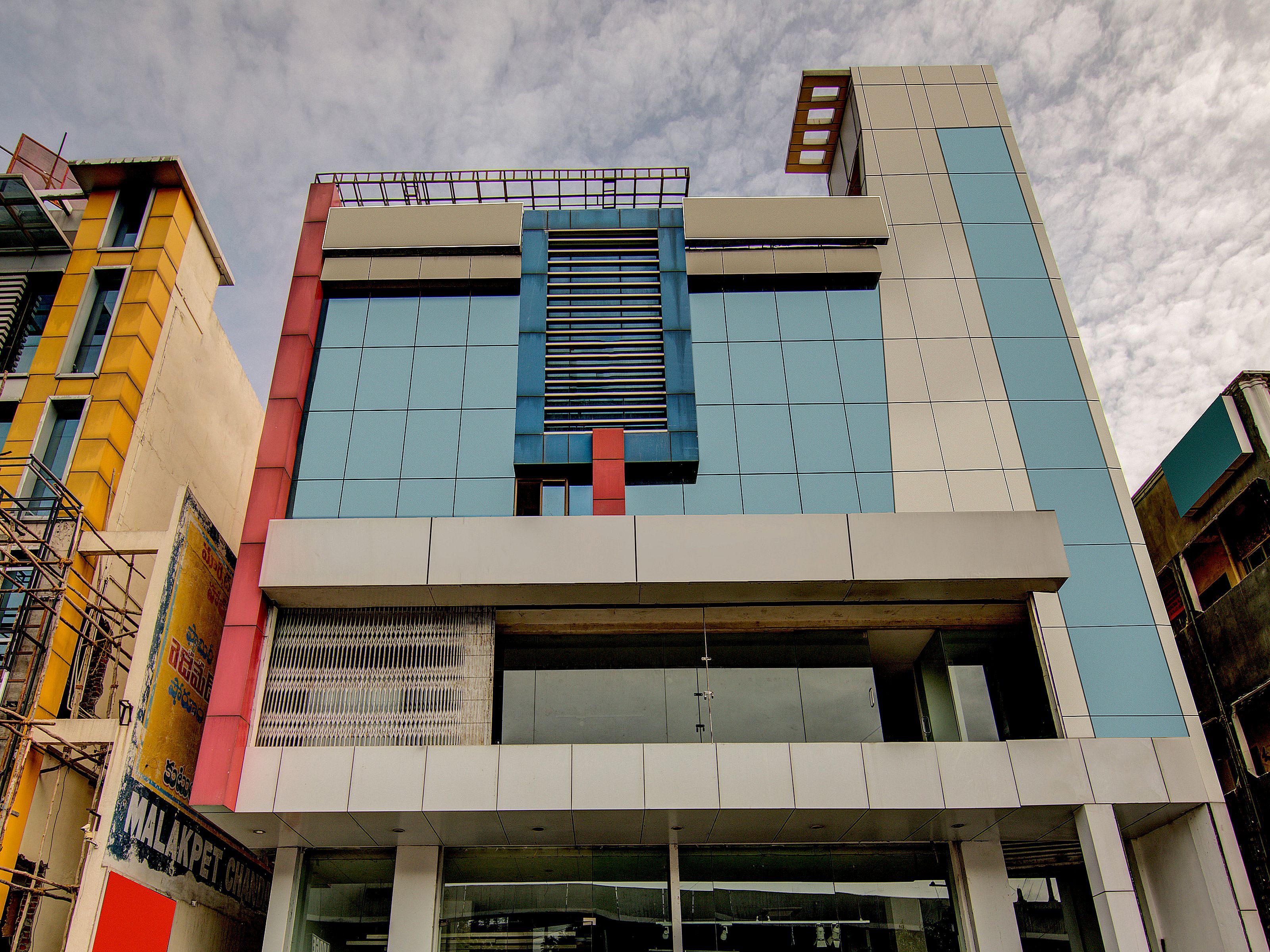 A multi-story building with a modern architectural design, featuring a mix of glass and solid panels, and a prominent central entrance.