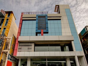 Un edificio de varios pisos con un diseño arquitectónico moderno, que combina paneles de vidrio y sólidos, y una entrada central destacada.