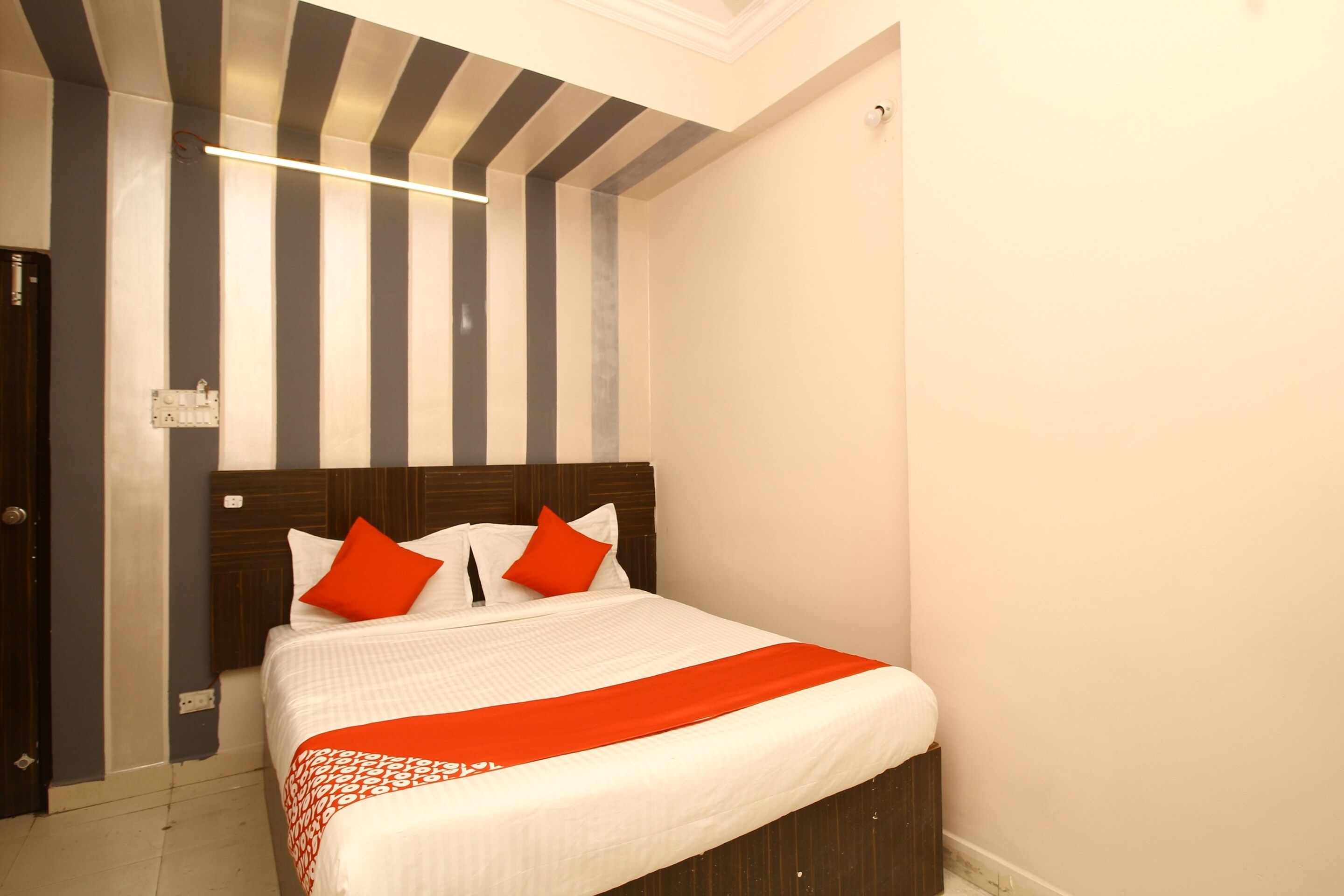 A hotel room with a bed, striped wall, and a ceiling light.