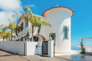A coastal building with a white facade, a red-tiled roof, and a gated entrance. - Blue Sea Tower plus Guest Villa  (CALHETA)