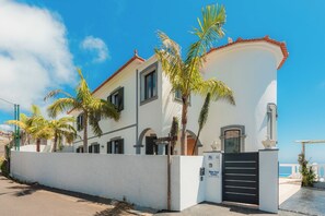 A white building with a red-tiled roof, multiple windows, and a gated entrance. - Blue Sea Tower plus Guest Villa  (CALHETA)