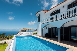 A modern hotel with a large swimming pool, a covered outdoor seating area, and a view of the ocean. - Blue Sea Tower plus Guest Villa  (CALHETA)