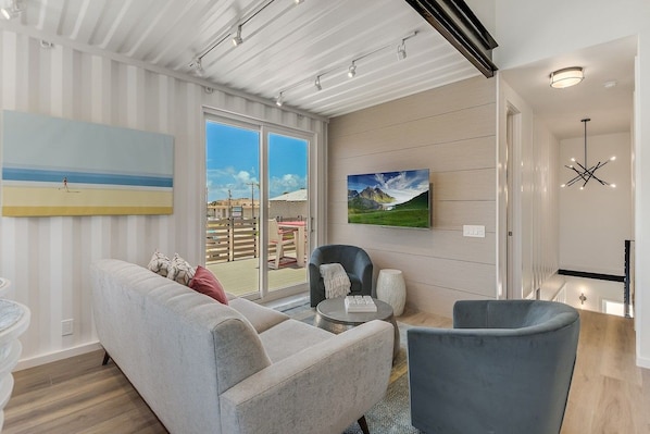 A modern living room with a sofa, armchairs, a coffee table, and a painting on the wall.