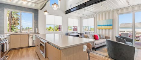 Una cocina moderna con una isla grande, armarios de madera y electrodomésticos de acero inoxidable.