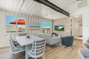 A modern interior with a dining area, a sofa, and a TV mounted on the wall.