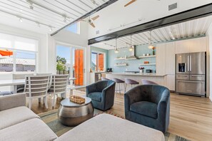 A modern kitchen with a stainless steel refrigerator, a bar area, and a dining space with a table and chairs.