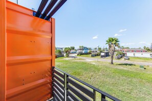 A view from inside a building looking out to a residential area with houses, palm trees, and a clear sky.