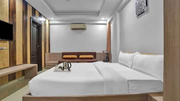 Una habitación de hotel con una cama, un televisor, una mesita de centro y aire acondicionado instalado en la pared.