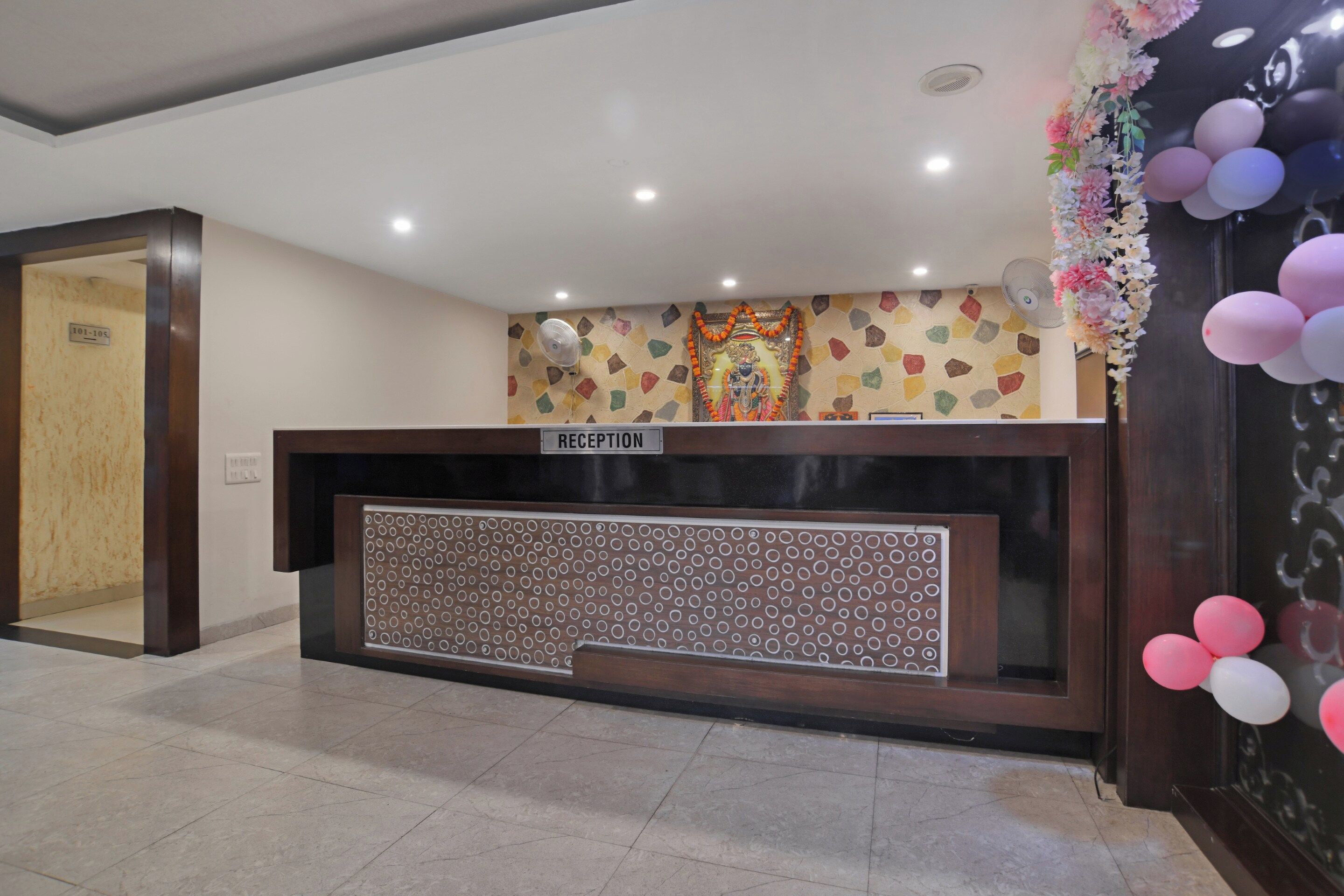 A reception desk with a sign, a patterned wall, and a ceiling fan.