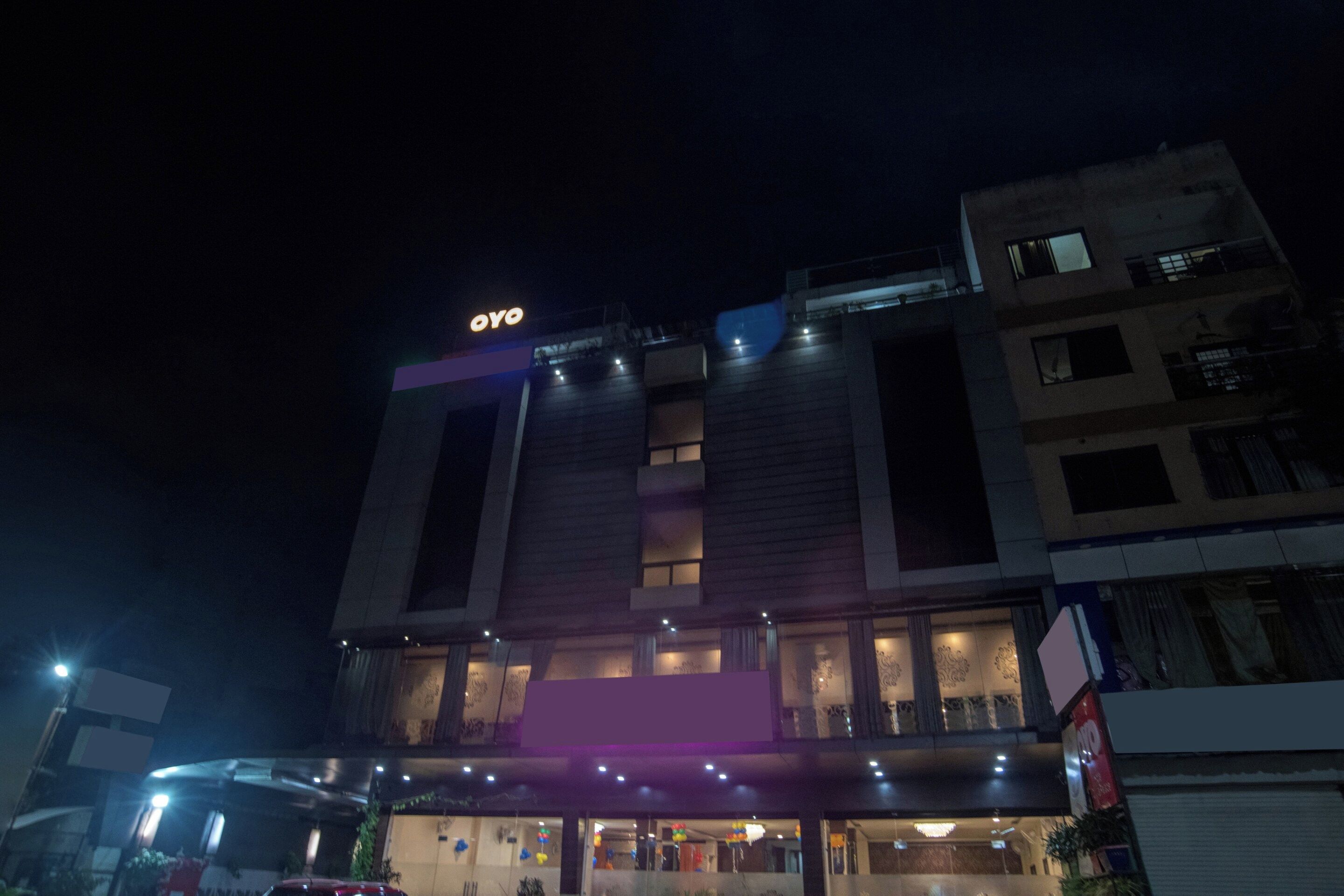 A building with a prominent 'OYO' sign at the top, multiple floors, and a covered entrance area.