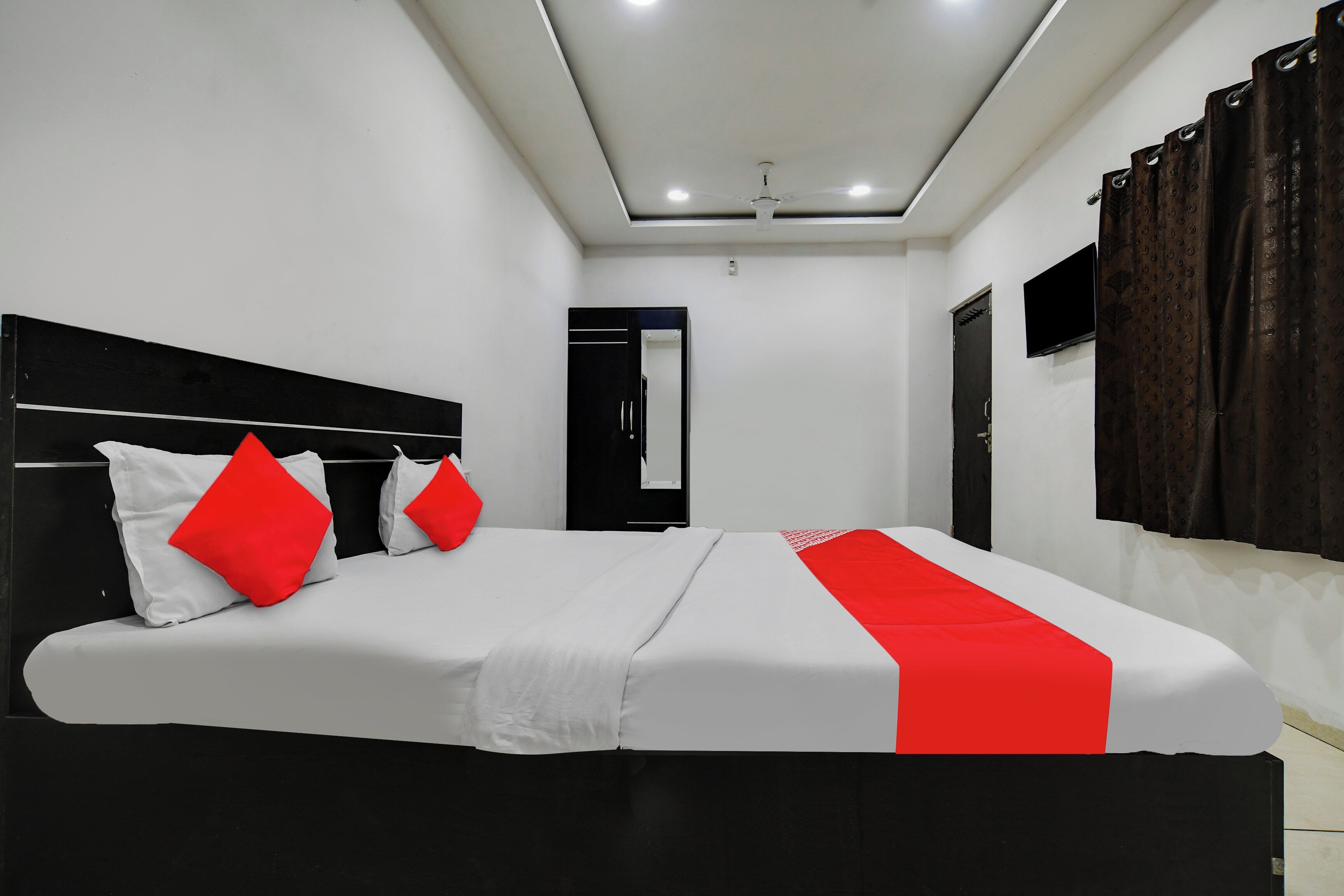 A modern hotel room with a large bed, a flat-screen TV, and a ceiling fan.