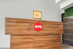 En receptionsdisk med træfacon og et rødt, rundt logo.