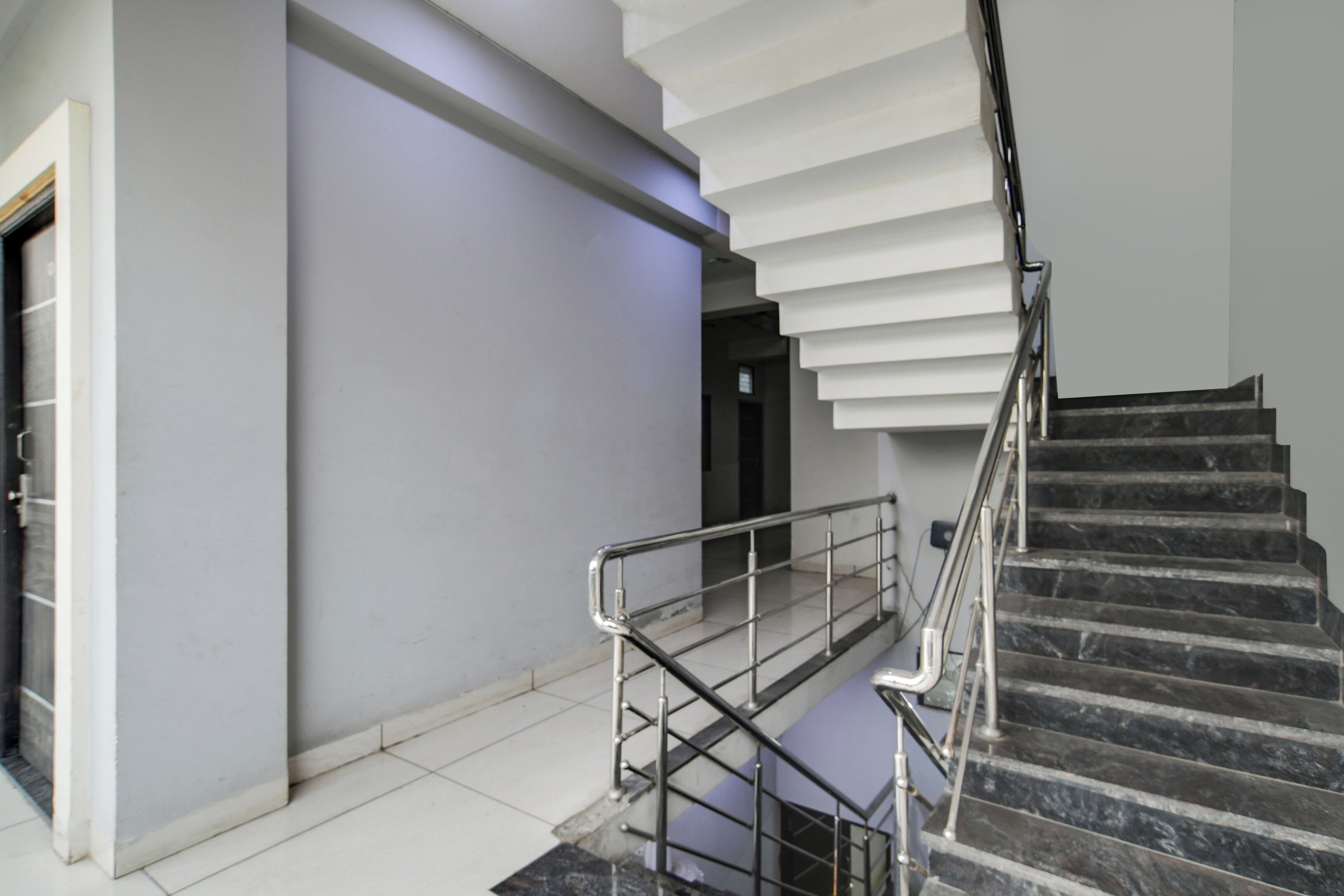A modern staircase with a metal railing, leading to an upper floor.
