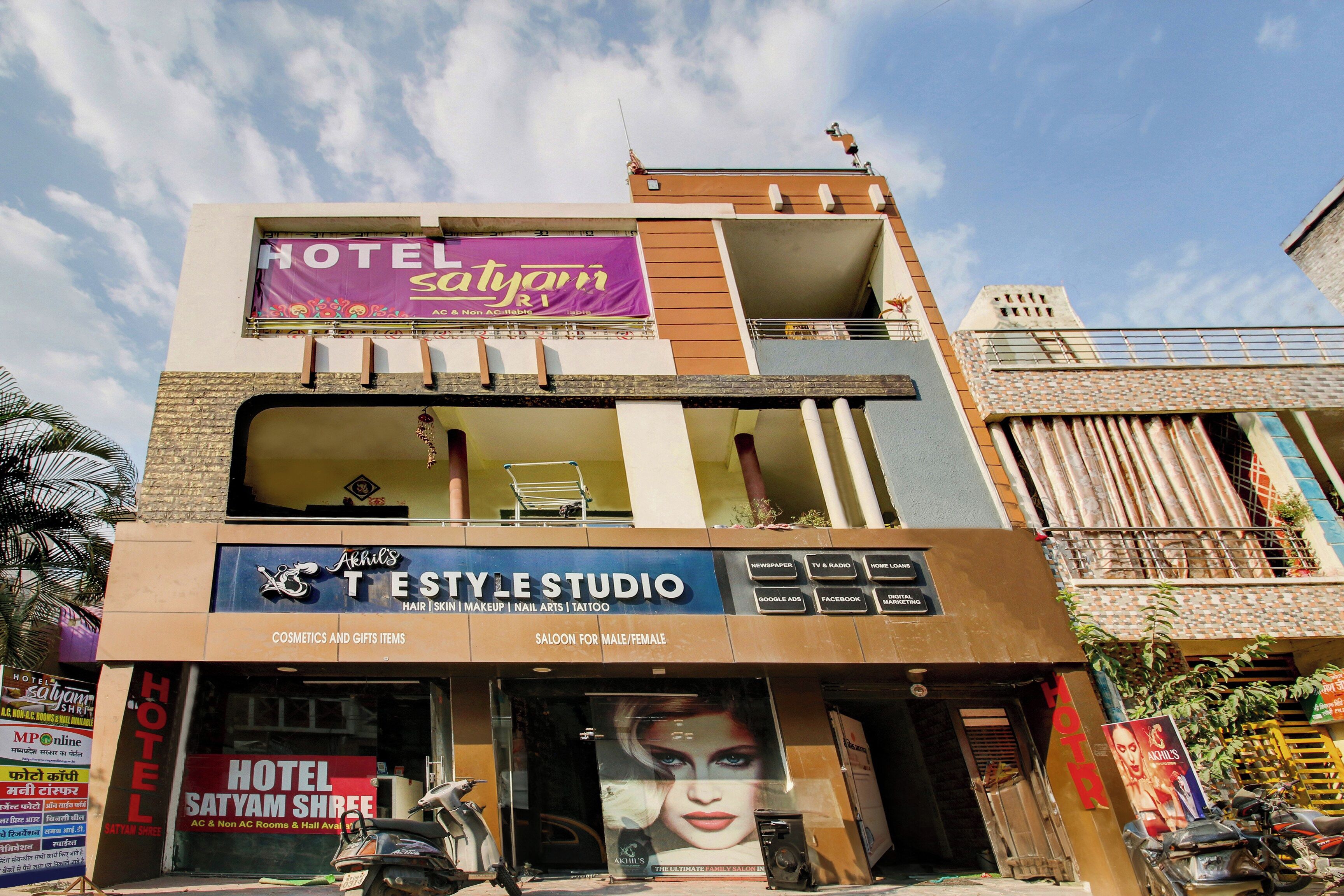A multi-story building with a visible ground-floor salon named 'Akhil's Style Studio' offering hair, skin, makeup, nail arts, and tattoo services.