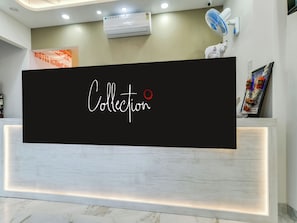 Una mesa de recepción con un gran letrero negro que dice 'Collection' y una pared blanca con un cuadro enmarcado.