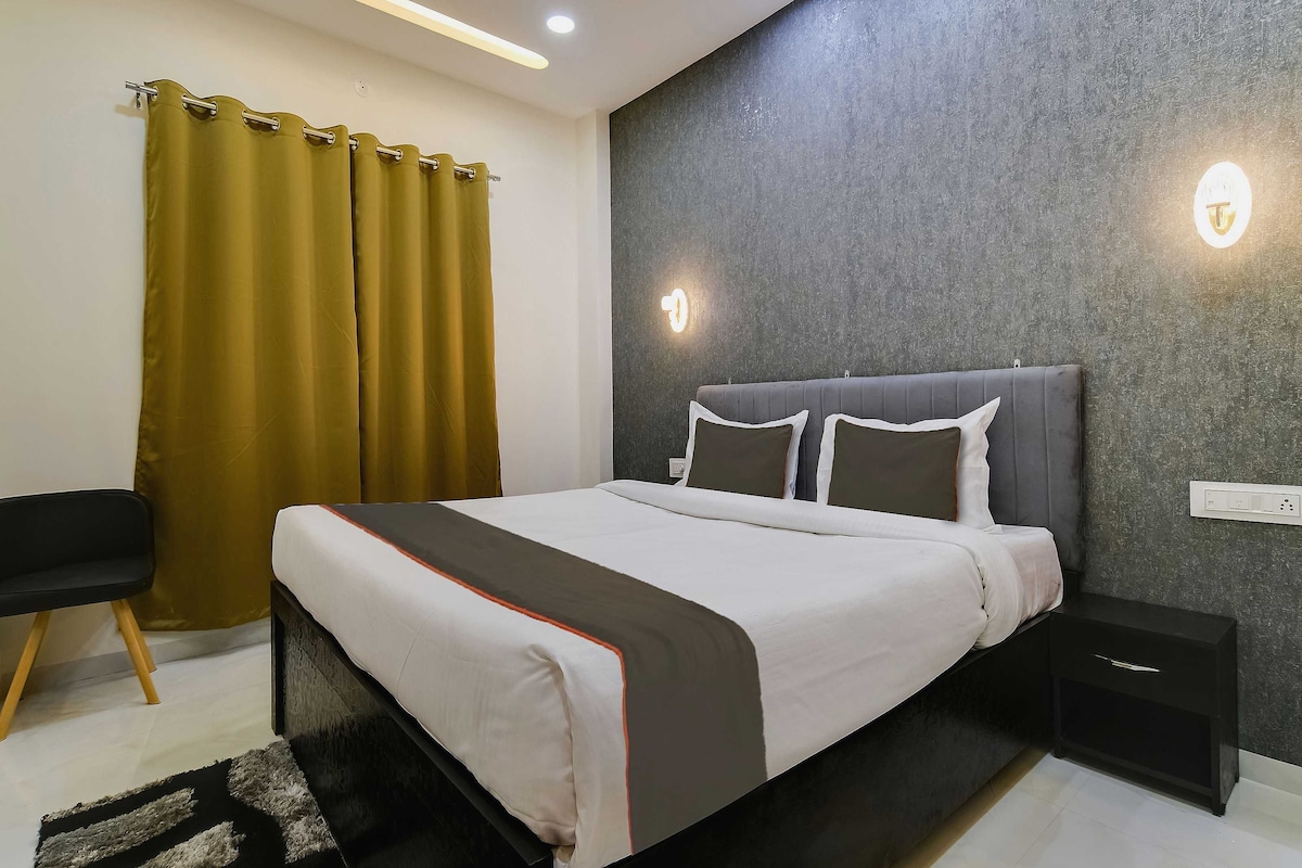A modern hotel room with a bed, bedside tables, a chair, and a curtain.