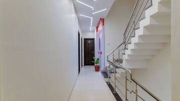A modern hotel hallway with a staircase, a potted plant, and a sign on the wall.