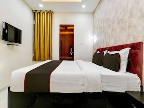 A hotel room with a bed, a television, a door, and a curtain. - Hotel O by OYO Iconic Stay (Indore)