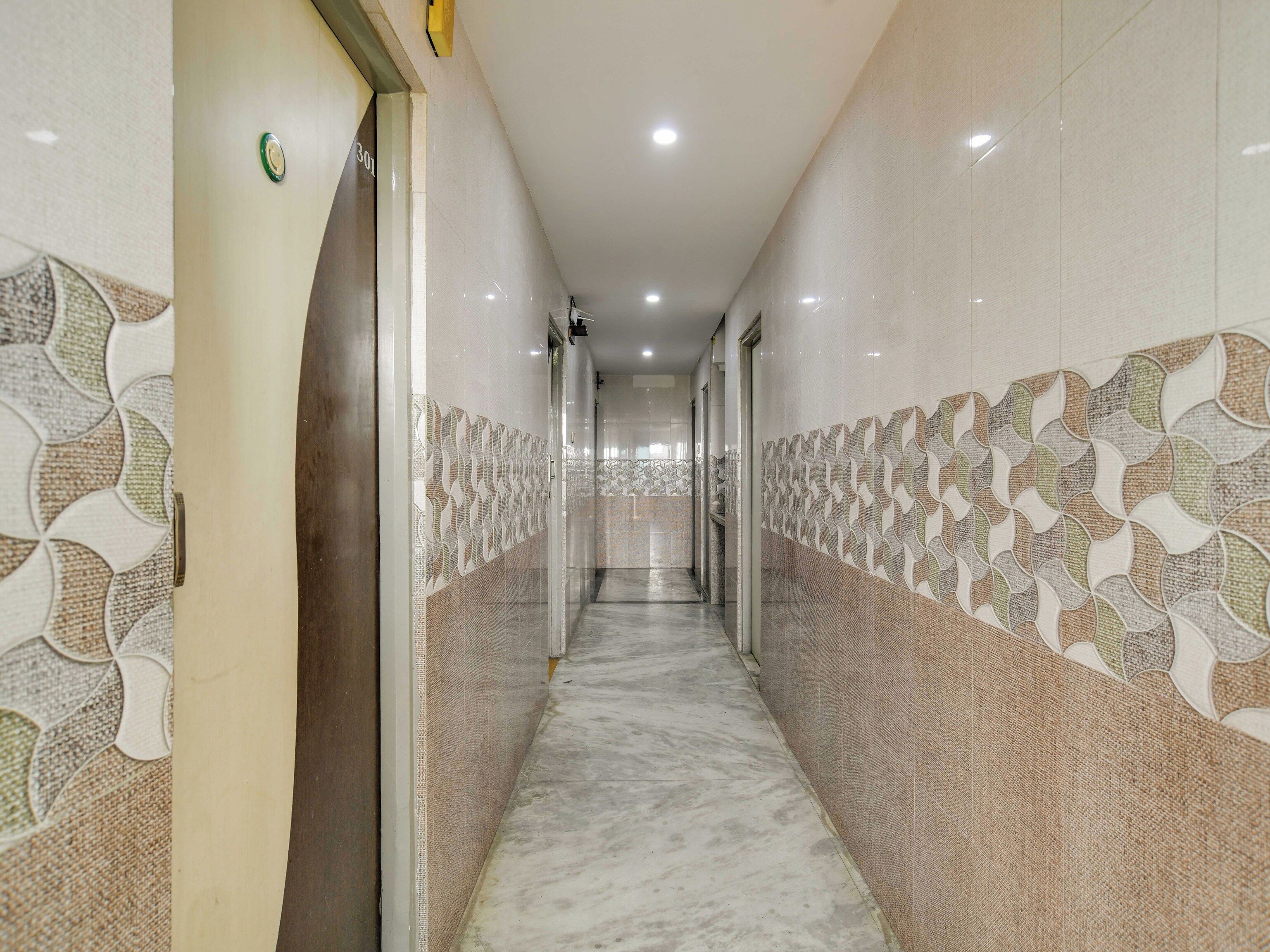 Un pasillo con paredes decoradas y suelo de mármol, que conduce a una puerta con una placa de número.