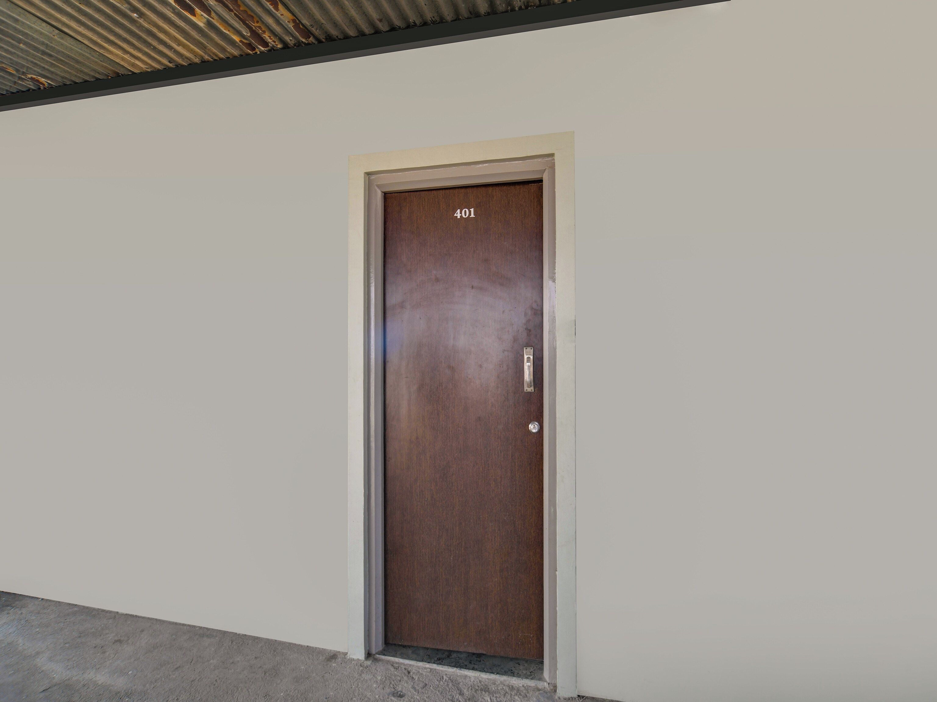 Una puerta con el número 401, un picaporte metálico y un pequeño candado circular.