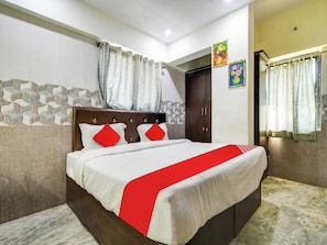 A hotel room with a bed, curtains, a wardrobe, and a wall with a patterned design. - Hotel O BR Greens (Indore)