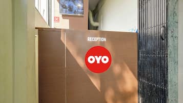 Un área de recepción con un letrero que dice 'RECEPTION', un logo 'YOYO', un cartel de 'NO FUMAR' y una cámara de seguridad.