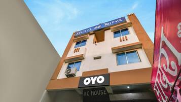 Un edificio de hotel con un letrero que dice 'HOTEL NITVA' y 'OYO AC HOUSE', indicando un hotel y una casa con aire acondicionado.
