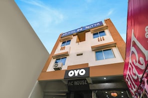 Un bâtiment d’hôtel avec une enseigne indiquant « HÔTEL NITVA » et « OYO AC HOUSE », ce qui signifie qu’il s’agit d’un hôtel et d’une maison climatisée.