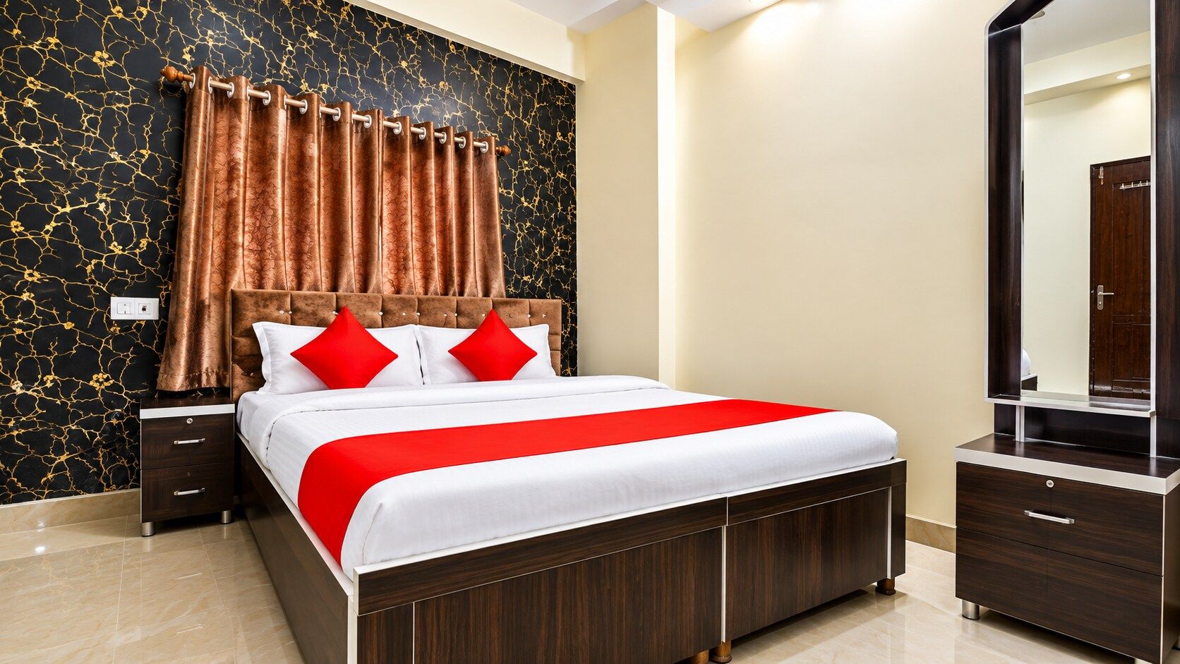 Una habitación de hotel con cama, mesitas de noche, cómoda y un espejo grande.