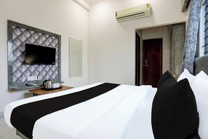 A hotel room with a bed, a flat-screen TV mounted on a marble-patterned wall, an air conditioning unit, and a door leading to another room. - Hotel O Grand Embassy (Indore)