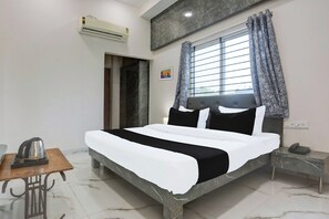 A hotel room with a bed, a bedside table with a phone, a kettle, and a picture on the wall. - Hotel O Grand Embassy (Indore)