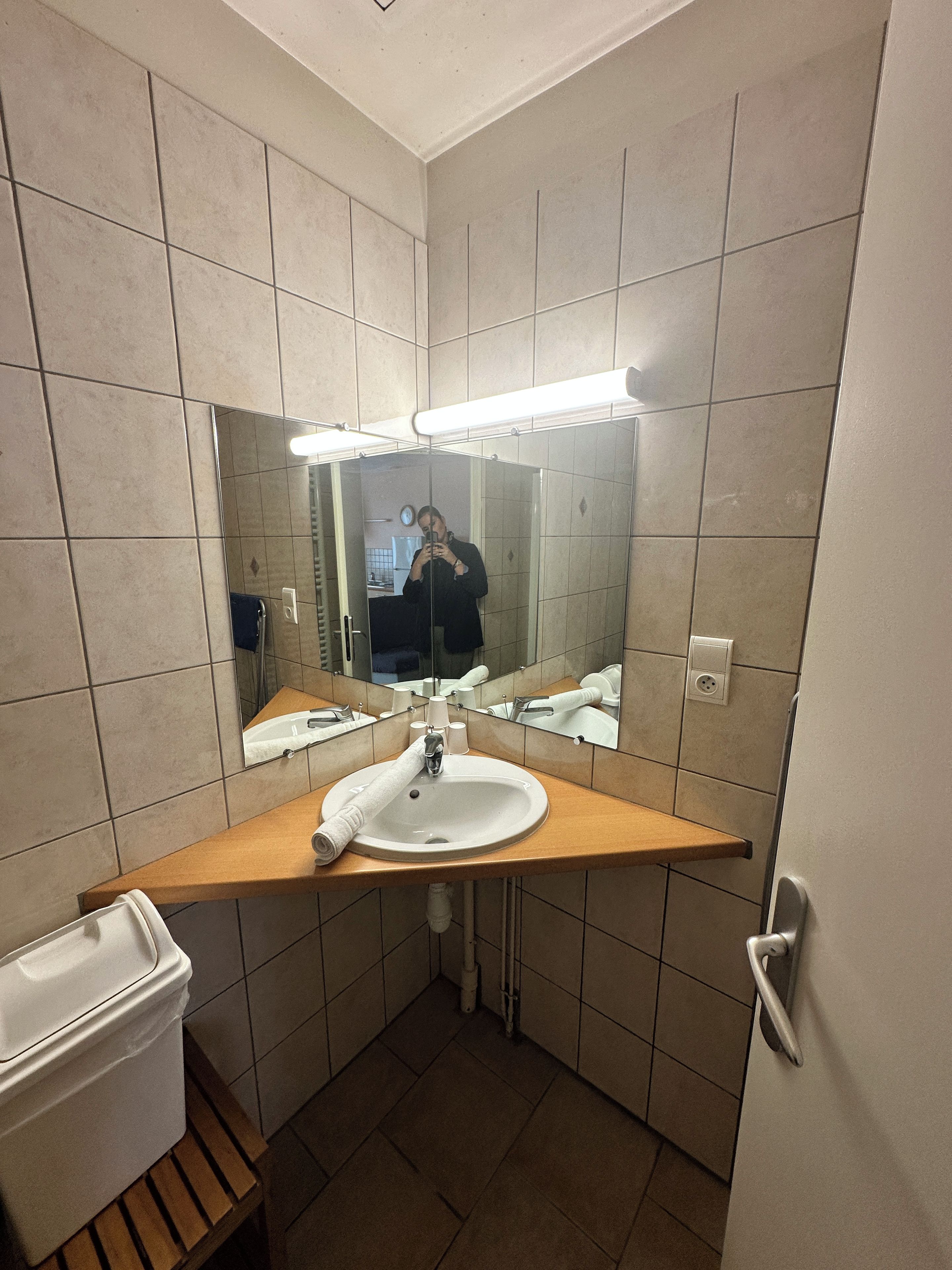 A bathroom with a sink, mirror, and a towel dispenser.