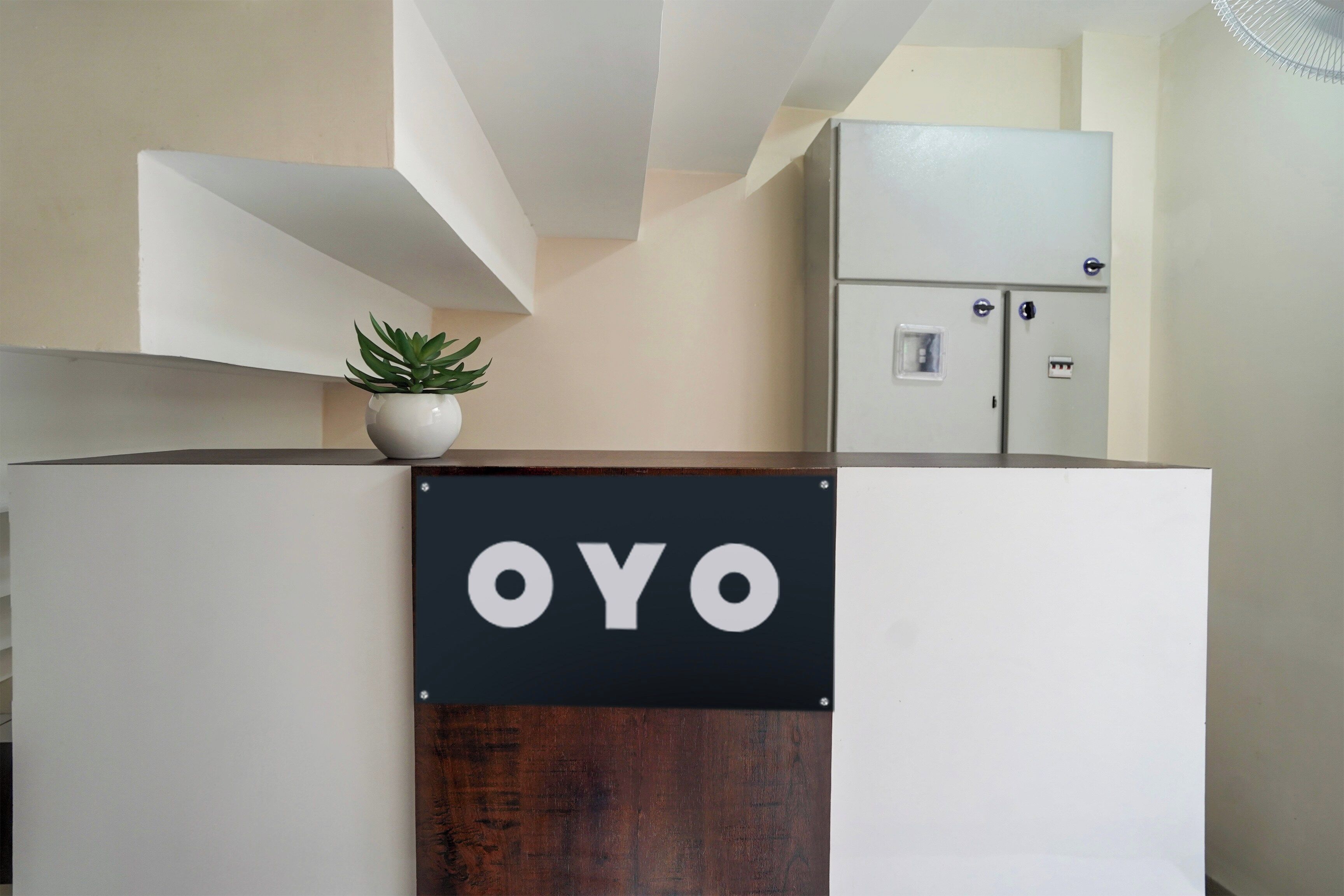 A reception desk with a sign that reads 'OYO' and a potted plant on top.