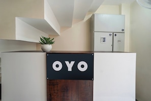 Una recepción con un cartel que dice 'OYO' y una planta en la parte superior.