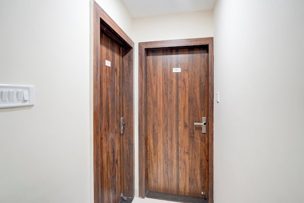 Un pasillo con dos puertas de madera, cada una con un picaporte de metal y una pequeña etiqueta encima.