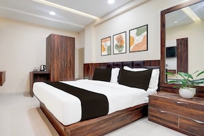 Un dormitorio moderno con una cama grande, un armario de madera, mesitas de noche y un espejo.