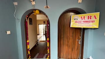 Un pasillo con dos puertas de madera, una con un cartel que dice 'AURA SLECE HOMESTAY KODAKANAL' y otra cerrada.