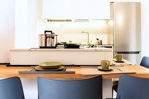 A modern kitchen with a stove, sink, and a stainless steel refrigerator. - New Listing (Milano)