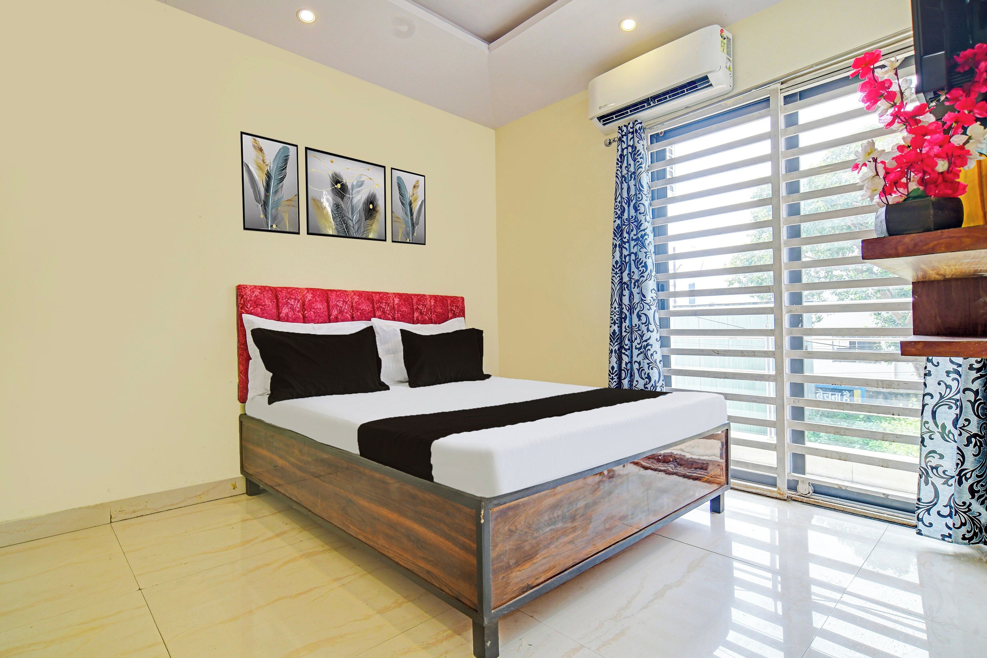 A bedroom with a bed, a window with blinds, and an air conditioning unit.